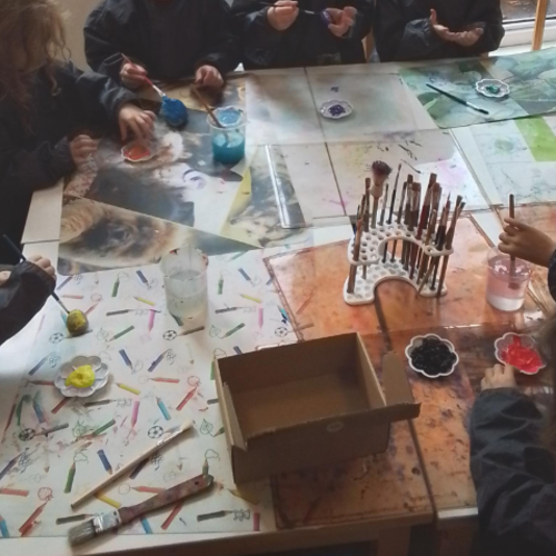 Die Kinder malen Steine bunt an, um diese dann in die Kiste zu legen.